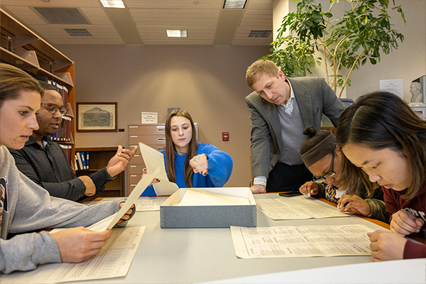 students and professor examining documents