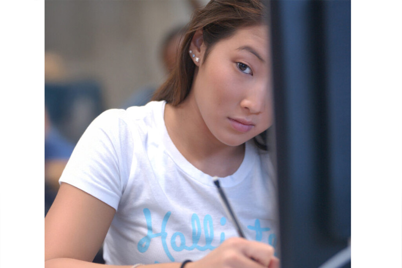 student writing in notebook with a pencil