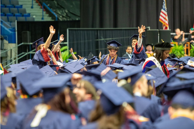 students waving at commencement
