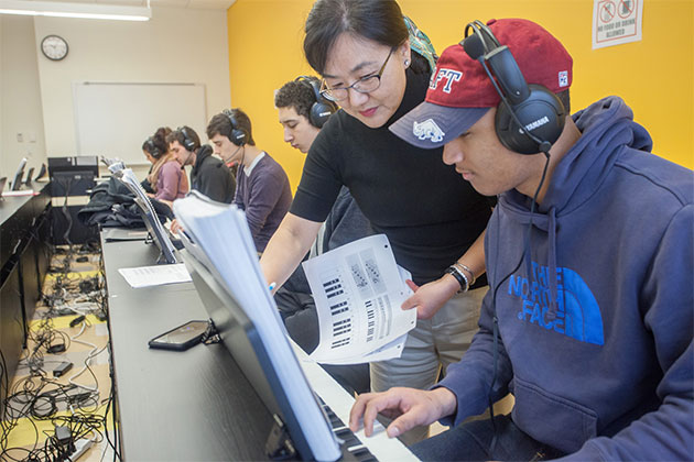 Professor instructing student playing piano