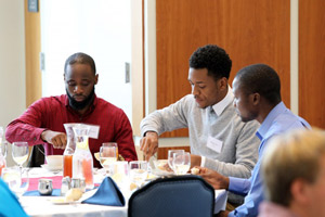 Three students dig into an appetizer at the business luncheon