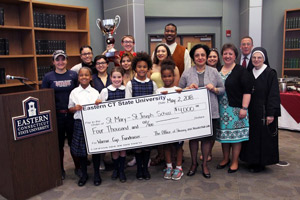Children from St. Mary-St. Joseph School (SMSJ) help Eastern President Elsa Nunez hold the check for a group photo with Burr Hall residents and other Eastern and SMSJ staff.