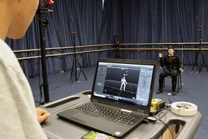 Using motion-capture technology, the student in the background is rendered as a 3D image on the computer.