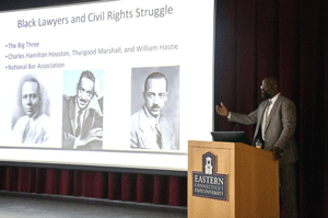 Professor Davis Canton stands at the podium while he presents