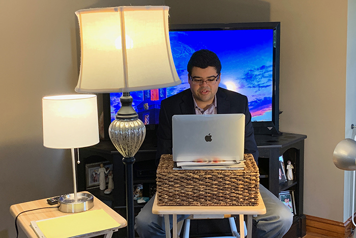 From his living room, Tyler Madden utilizes an arrangement of lamp lighting and a backdrop on his television monitor to give the ETV newscast an in-studio feel. 