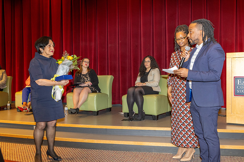 President Núñez accepts flowers from Joshua Sumrell, coordinator of the Intercultural Center, and Starsheemar Byrum, director of the Women's Center before speaking at the "Shades of Success" forum