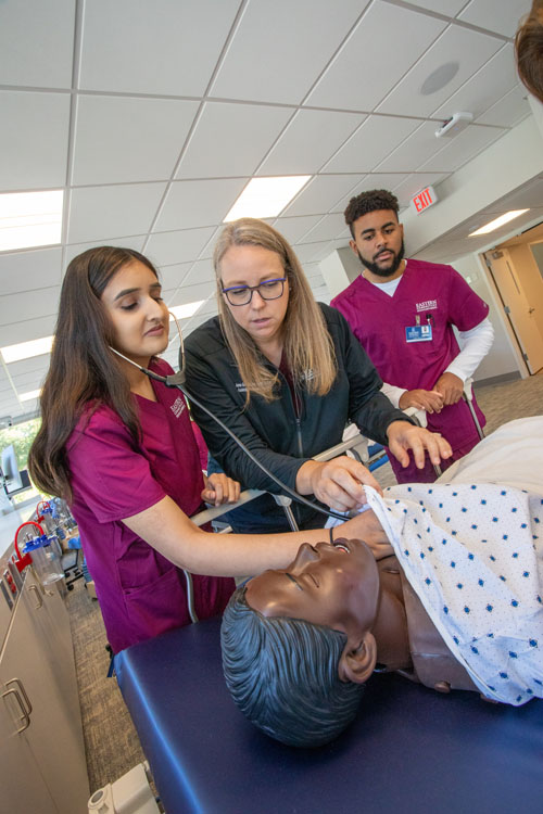 Nursing students demonstrate nursing simulation lab equipment