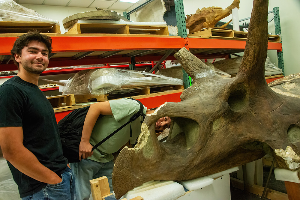 Two students pose with a dinosaur skull.