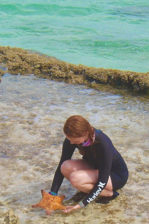 A student holds a starfish in the Bahamas.