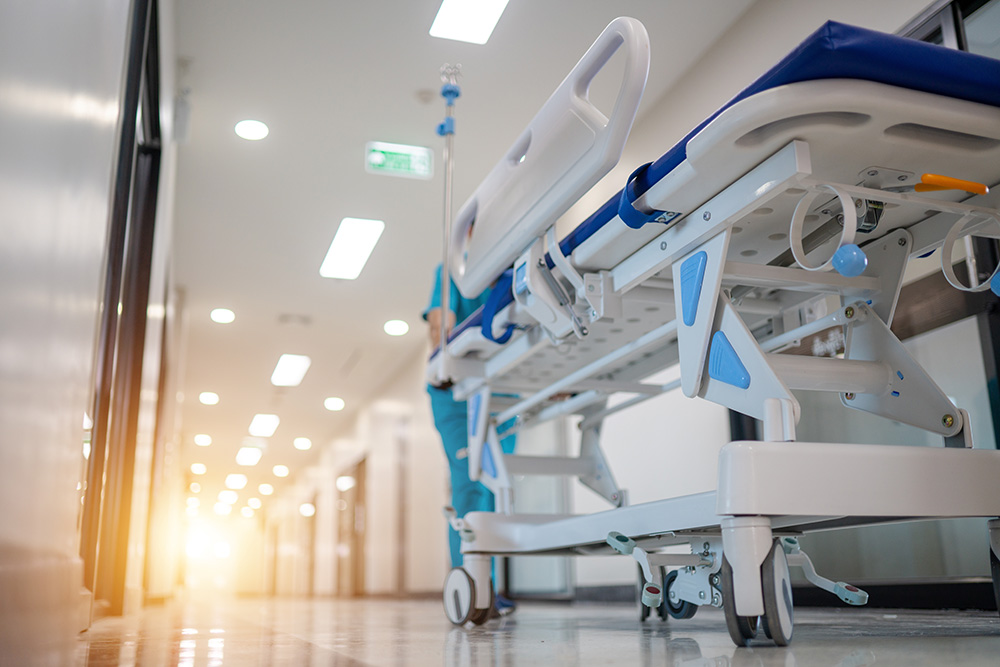 A stock image of a hospital bed in a hospital hallway