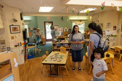 A parent and child speak with a teacher in a classroom.