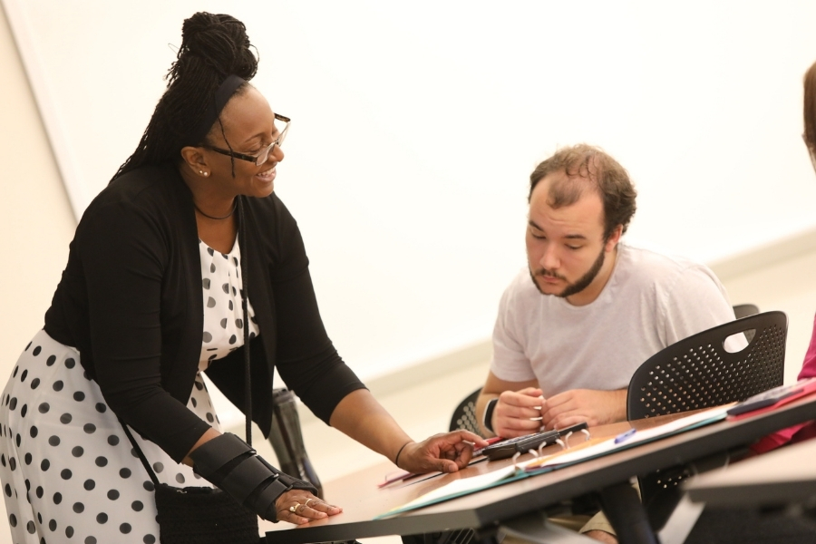 Kim Ward is teaching mathematics to a student in a classroom. 