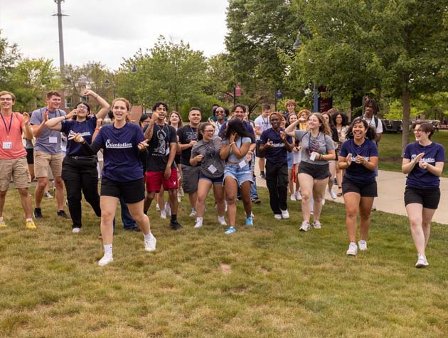 students walking across the grass on campus