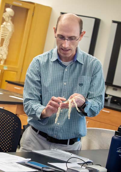 Professor Kurt Lucin holding a skeleton hand