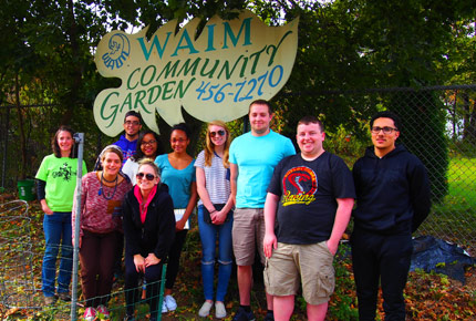 Students posing in front of WAIM Commnunity Garden sign