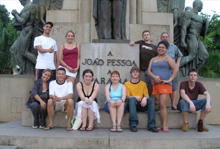 Students and professor posing in front of a statue