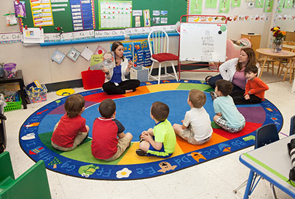 Student teacher reading a book to children