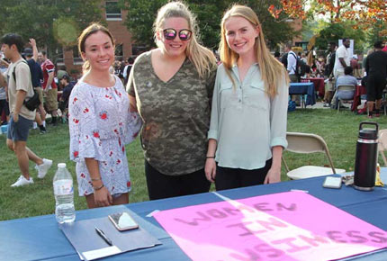 Students standing behind table with sign for Women in Business club