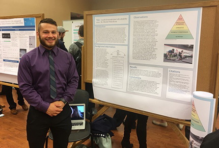 Student posing for photo next to research presentation