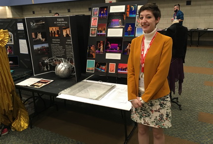Student standing in front of presentation material