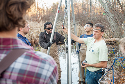 Professor and students working in a swamp