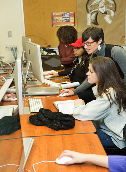 Student working on computer with professor overseeing