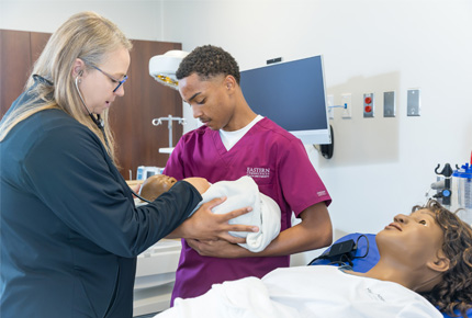 nursing professor and student interacting with a practice nursing dummy