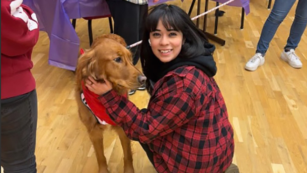 a student posing for a photo with a dog