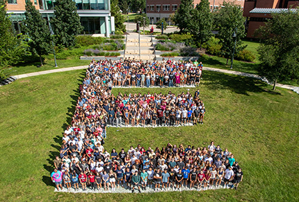 students posing for photo, gather in the shape of a large E