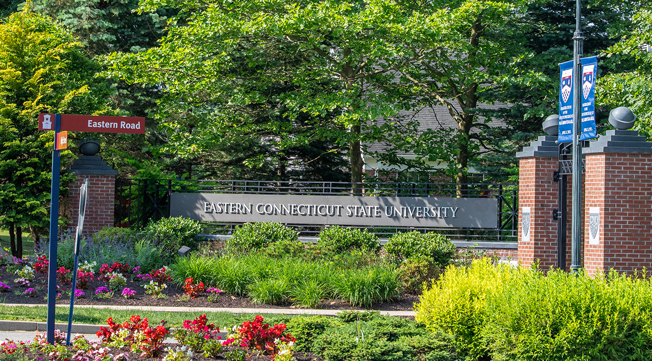 the entrance sign to Eastern Connecticut State University with blooming summer flowers in the foreground