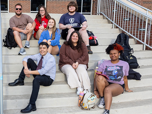 Martin Mendoza-Botelho sittong on the steps of the library with students